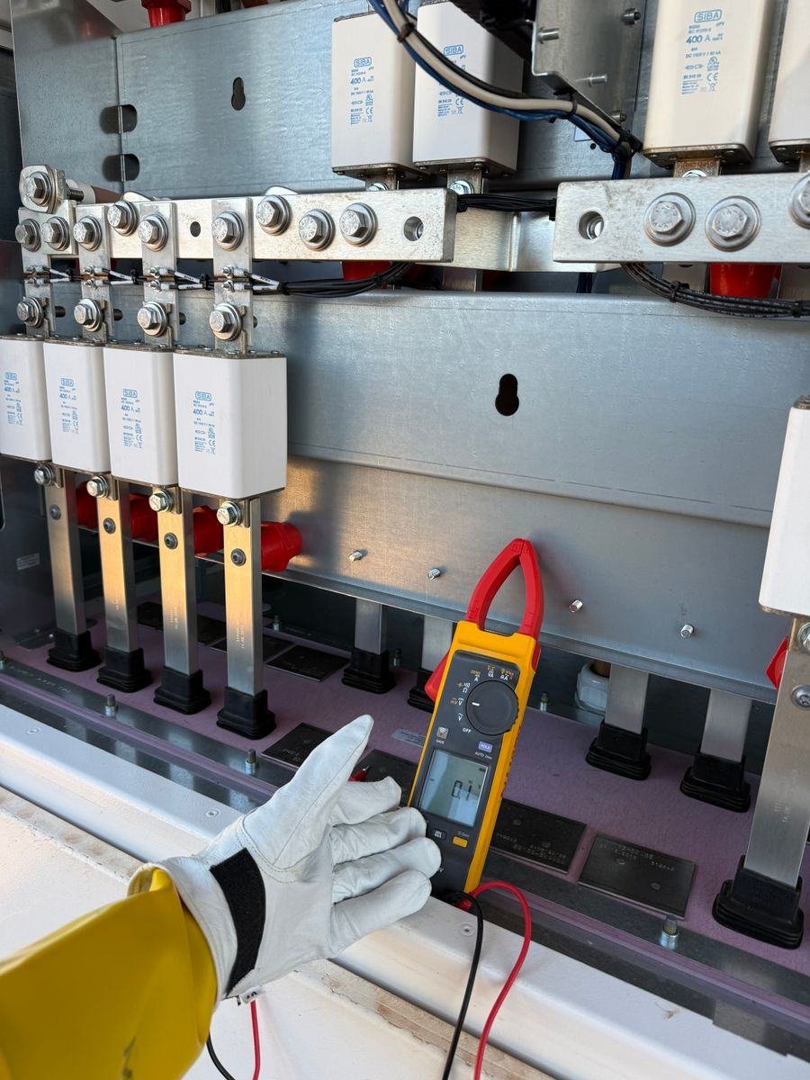 Clamp meter measuring current on copper busbars in a panel